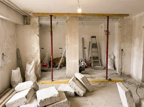 Chantier de rénovation intérieur avec mur en briques apparentes et poutre métallique endommagée